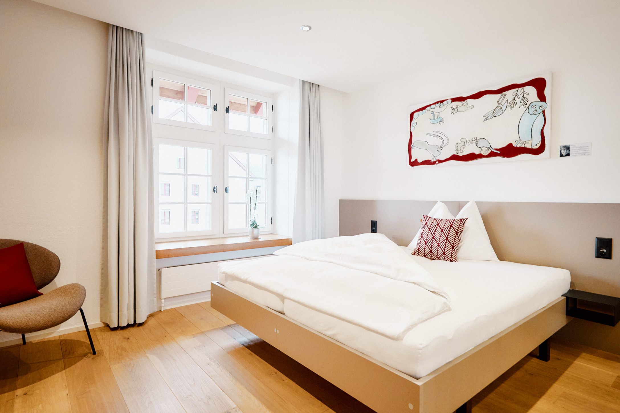 Helles Hotelzimmer mit Doppelbett und natürlichem Licht durch grosse Fenster im Hotel zum Schneggen in Reinach AG
